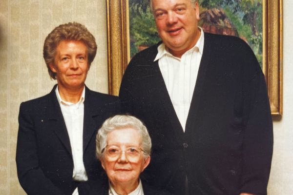 Elfriede Hansen sitzt auf einem Stuhl vor den stehenden Helga und Jürgen Hansen